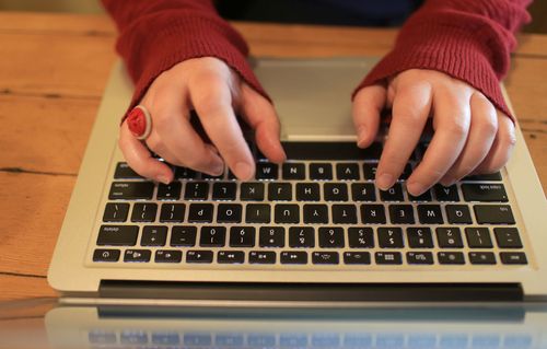 Hands typing on a laptop