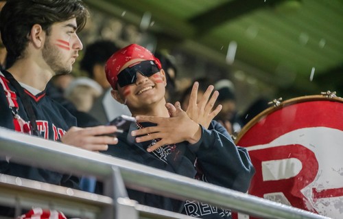 A man in sunglasses and bandana giving a high five to another man.