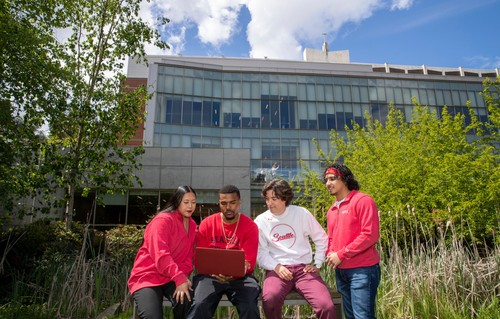 A group of people sitting on a bench outside of a building.
