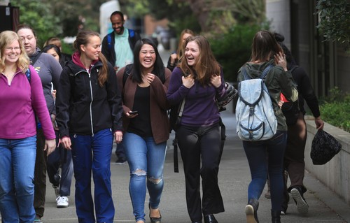 A group of people walking down a sidewalk.