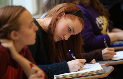 Woman Taking Notes in Classroom