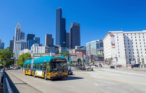 A Seattle bus on the highway with a backdrop of Seattle buildings