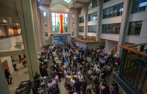 Networking event in a modern atrium with attendees mingling.