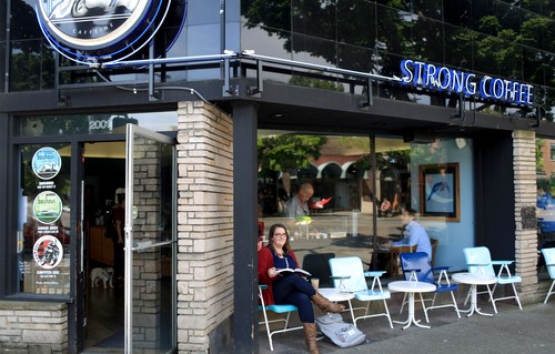 A student reads outside on a nice day at a coffee shop in Ballard, Seattle