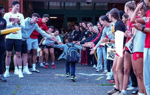 A photograph of a student in elementary school giving high-fives to Seattle U students