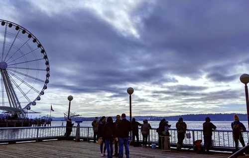 Visitors to Seattle walking by the pier next to the ferris wheel.