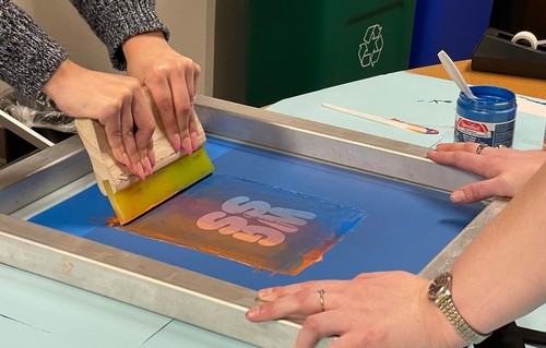 students screen printing a t shirt with the letters WGSS