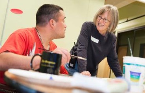 A JV Encorps Volunteer talking to a male in an artroom