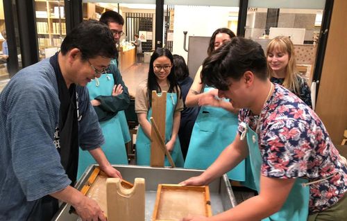 two men making Japanese paper with wooden sieves and 4 people watching