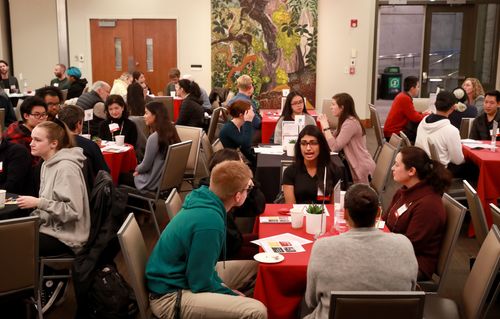 Groups of students talk around tables
