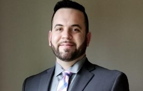 Justin's headshot, wearing suit and tie