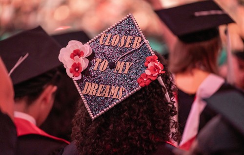 Black graduation cap decorated with flowers and with the words “Closer To My Dreams”