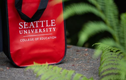 Seattle University COE red bag in green foliage