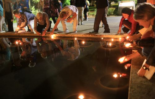 SU community placing candles in the reflection pool