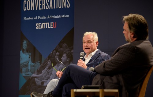 two men sitting on stage and talking