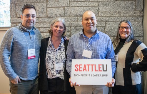 Four people in front of brick wall smiling holding Nonprofit Leadership sign