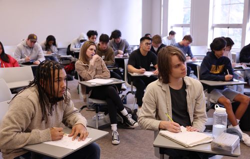 A classroom of students sitting in desks and listening