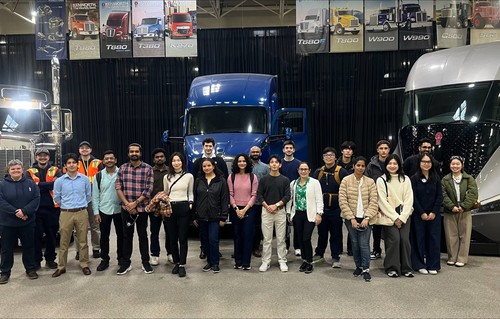 Albers students and PACCAR hosts stand together in front of Kenworth trucks during a company trek to PACCAR.