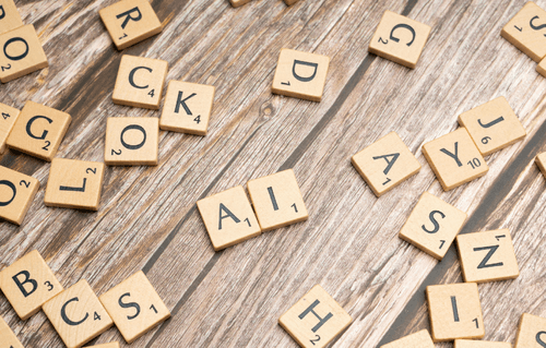 Scrabble tiles on a wood background, spelling A.I. in the middle