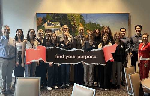 Erin Vernon with Economics faculty and students, with banner that says Find Your Purpose