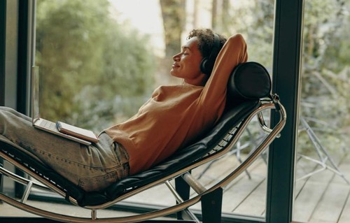 Woman on headphones listening while on lounger