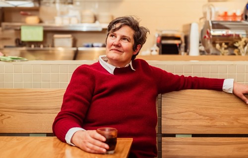 Alumnus Jody Hall sitting at a table with cup of coffee
