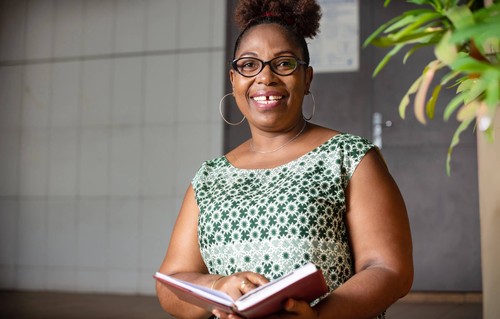 A woman in glasses holding a notebook