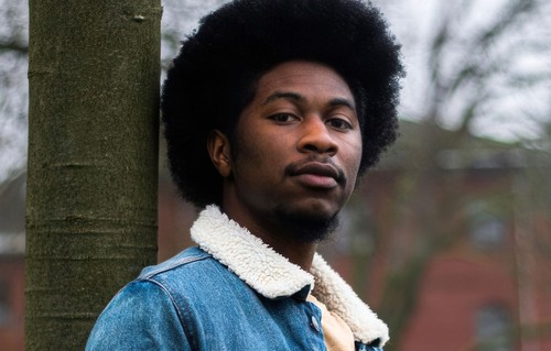 A young man leaning against a lamp post