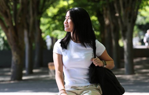 A student sitting under a canopy of trees