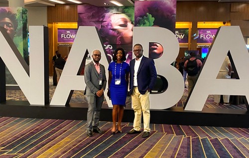 Three people standing in front of a NABA sign