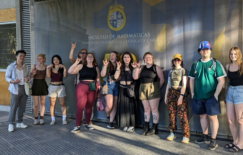 Students stand in front of a mural while on spring break in Chile.