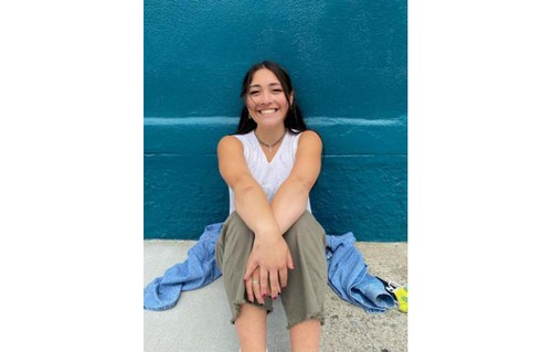 Allison Namba smiling in front of blue wall