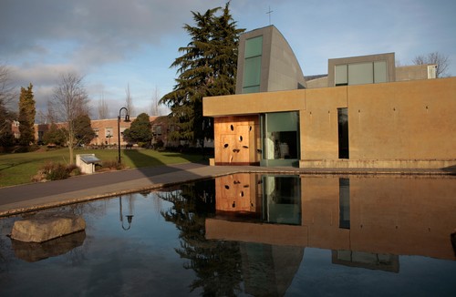 A modern building with a pond in front of it.
