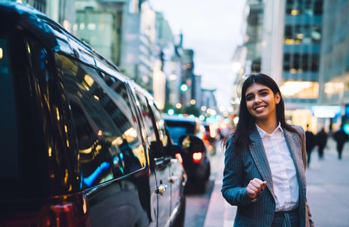 Female exec standing by a black SUV