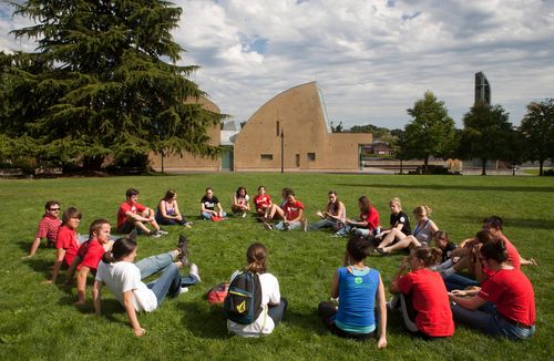 Large group of students sitting on green grass