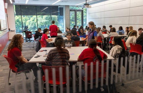 Professor talks to students in a busy classroom