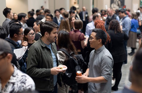 Two men talking to each other in a crowded room