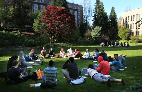A group of people sitting on grass in a park.
