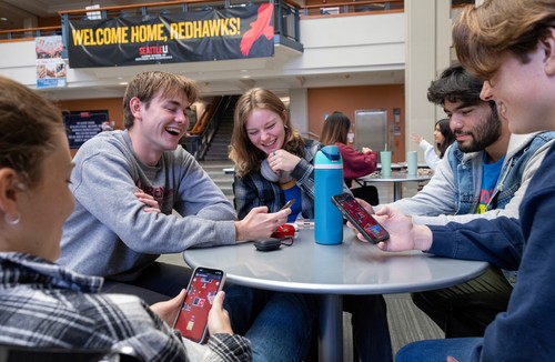 A group of people sitting around a table with cell phones.
