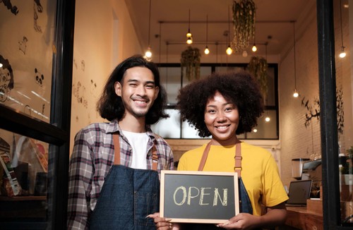 Two shop owners with an Open sign