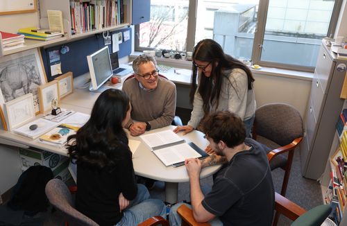Students sitting around desk with faculty member