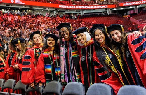 Graduates in regalia at commencement smiling at the camera