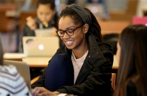 A grad student smiling while typing on a laptop computer